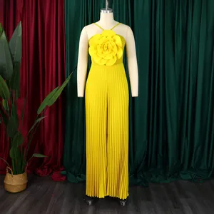 Detail of a bright yellow pleated jumpsuit with a large decorative flower on the chest.