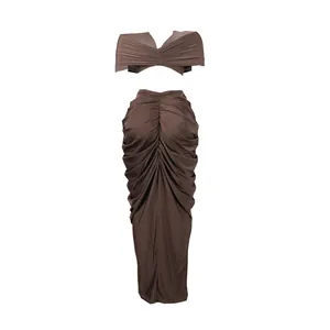 Detail view of brown two-piece set featuring a ruched crop top and long pleated skirt.
