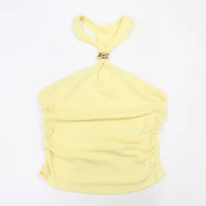 Dettaglio di un top halter giallo pallido con anello dorato e fianchi increspati