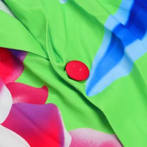 Detail macro view of a red fabric-covered button on a vibrant floral print suit jacket