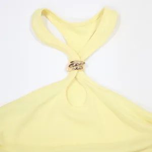 Primo piano del dettaglio halter con anello in metallo dorato su top giallo
