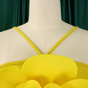 Detailed close-up view of a vibrant yellow jumpsuit featuring a large 3D flower decoration.