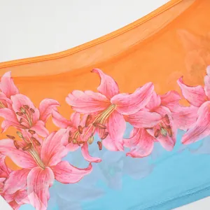 Detailed close-up of pink lily floral print on orange and blue gradient mesh fabric