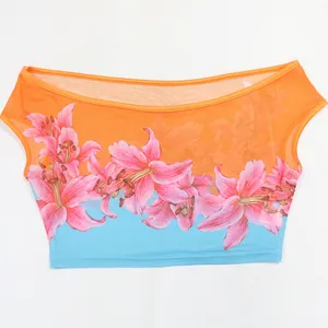Detail view of vibrant pink lily floral print on orange mesh off-shoulder crop top