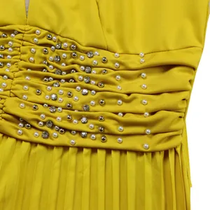 Detailed view of yellow jumpsuit featuring ruched waist with pearls and rhinestones