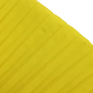Macro detail showing the texture of bright yellow pleated fabric for jumpsuit.
