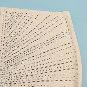 Primer plano de tela elástica beige con un intrincado patrón de pedrería radiante