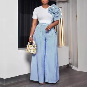 Modella indossa un set pantaloni larghi a righe blu con maxi rouche floreale sulla spalla