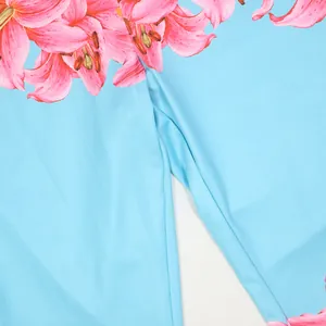 Close-up of vibrant pink lily floral print on sky blue high-waist fashion pants fabric