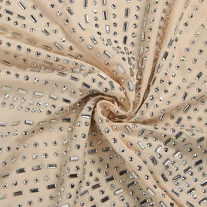 Detalle macro de tela de vestido champán decorada con pedrería plateada redonda y baguette
