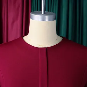 Gros plan d'une robe bordeaux avec col rond et détail de patte de boutonnage.