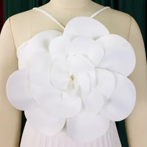 Close-up detail of the elegant large white 3D floral decoration on a pleated jumpsuit.