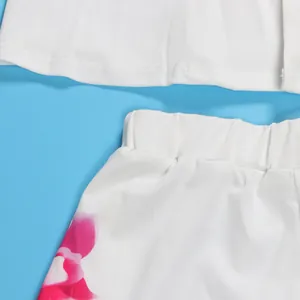 Close-up detail of white two-piece set featuring vibrant pink floral print on shorts