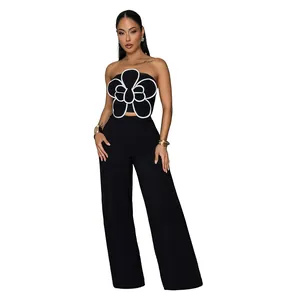 Détail d'un élégant haut bustier noir avec grande fleur 3D et pantalon large.