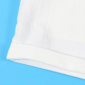 Close-up macro detail of white crepe fabric texture on minimalist sleeveless garment