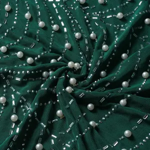 Detailansicht von dunkelgrünem Stoff mit Perlen und glitzernden Strasssteinen