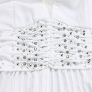 High-quality close-up detail of intricate pearls and rhinestones on white jumpsuit fabric