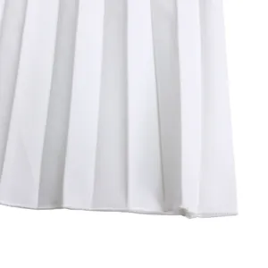 Macro view of white pleated fabric texture and fine stitched hem detail on a fashion garment.