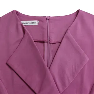Close-up detail of the V-neckline and brand label on a purple high-waisted dress.
