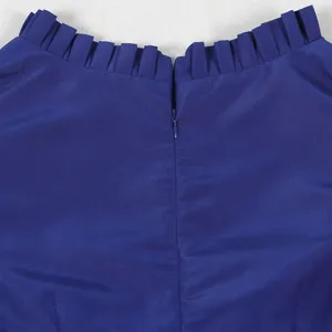 Nahaufnahme des Rüschenhalses und des unsichtbaren Rückenreißverschlusses am blauen Oberteil