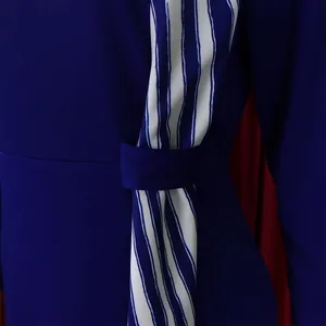 Détail d'une robe crayon bleue grande taille avec une ceinture rayée blanche et bleue.