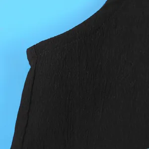 Detail shot of black textured fabric showing high-quality stitching on a halter top garment.