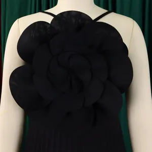 Close-up of elegant black 3D flower detail on a chic pleated jumpsuit bodice.