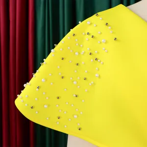 Close-up of elegant yellow evening dress with intricate pearl and bead shoulder details.