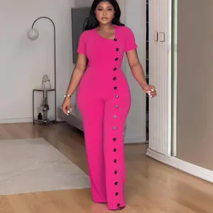 Dettaglio ravvicinato della tuta rosa a gamba larga con scollo irregolare e bottoni.