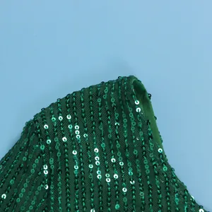 Close-up detail showing emerald green sequin embellishments on mesh fabric of a dress