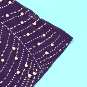 Detailansicht der eleganten Perlen und Strasssteine auf lila Netzstoff des Kleides
