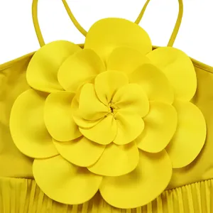 Detailed view of a yellow jumpsuit featuring a large 3D fabric flower and pleats