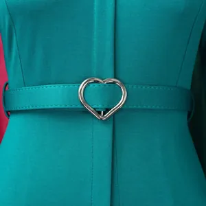 Gros plan d'une robe sarcelle élégante avec boucle de ceinture argentée en cœur