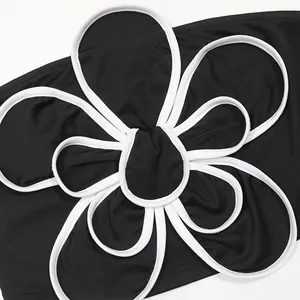 Détail en gros plan de l'élégante fleur 3D sur un haut bustier noir sans bretelles.