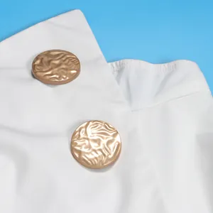 Detailansicht der goldfarbenen Knöpfe an einem weißen, elastischen Jumpsuit mit weitem Bein
