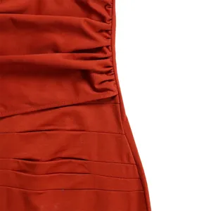Makro-Detailansicht der gerafften Faltenstruktur an diesem eleganten orangefarbenen Kleid