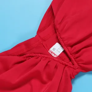 Close-up detail of red ruched bodycon dress showing the size tag and fabric texture