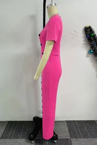 Vista laterale dettagliata di una tuta rosa vivace a maniche corte con bottoni decorativi.