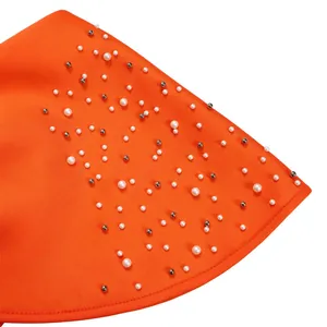 Detailed macro view of white faux pearls and silver beads on orange evening dress fabric