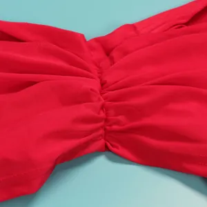 Detailed close-up of the elegant ruched fabric on a vibrant red two-piece evening gown.
