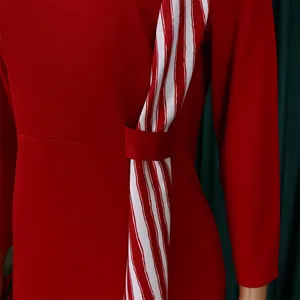 Détail d'une robe crayon rouge avec un ruban rayé rouge et blanc décoratif à la taille.