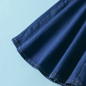 Dettaglio ravvicinato di pantaloni svasati in denim blu scuro con cuciture arancio