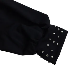 Close-up detail of black jumpsuit sleeve cuff with pearl and rhinestone beading