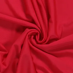 Macro view of vibrant red high-stretch fabric featuring elegant spiral pleated texture.