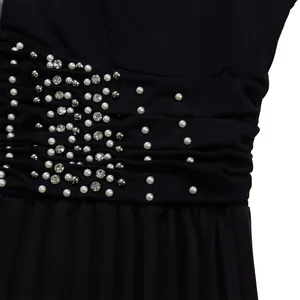 Close-up detail of pearls and rhinestones on a black ruched jumpsuit waistband