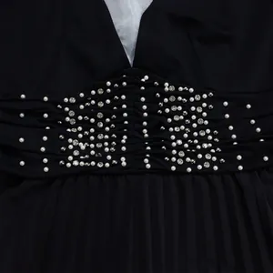 Close-up of elegant pearls and rhinestones on the ruched waist of a black jumpsuit