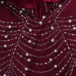 Detailansicht eines burgunderfarbenen Kleides mit feinen Strass- und Perlenakzenten
