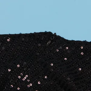 Close-up of black sequined fabric with a concealed zipper on a mesh dress