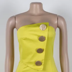 Detailansicht eines neon-gelben trägerlosen Overalls mit vier goldenen Zierknöpfen.