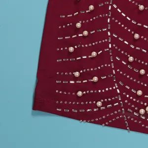 Detaillierte Nahaufnahme von Strasssteinen und Perlen auf weinrotem Bodycon-Kleid